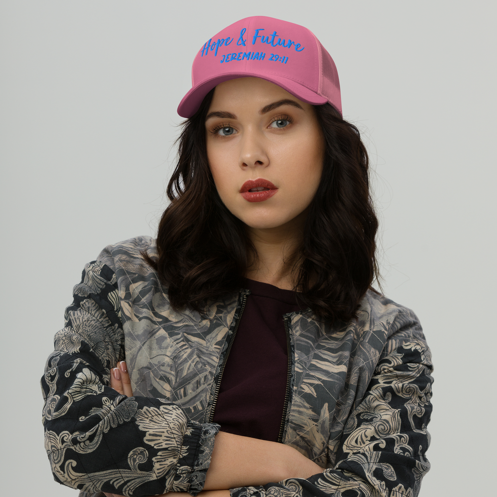 Woman wearing a pink cap with colorful text and graphics on a plain background
