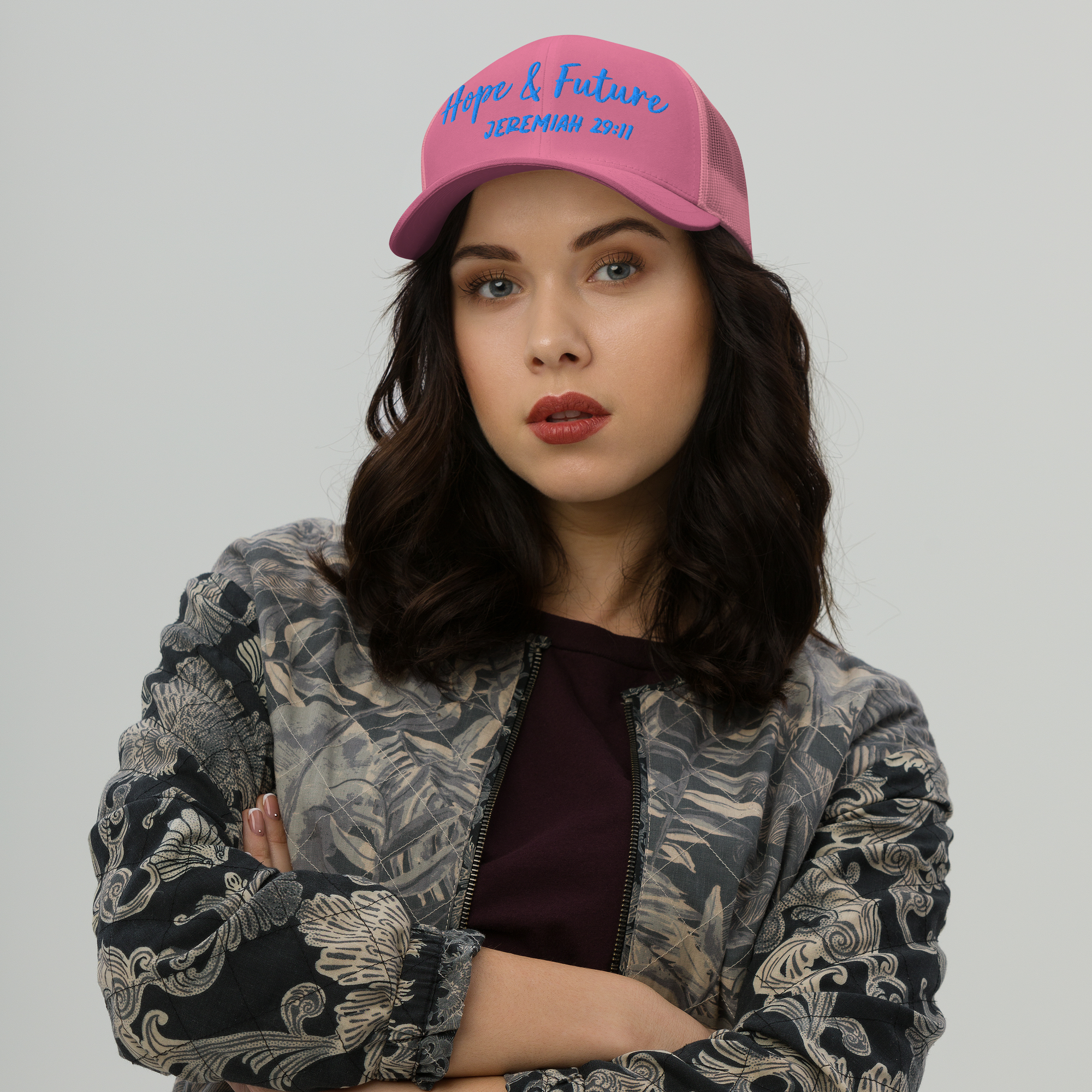 Woman wearing a pink cap with colorful text and graphics on a plain background